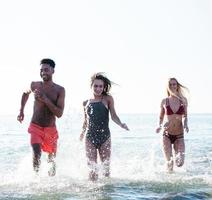 groep van vrienden rennen in de zee. concept van zomertijd foto