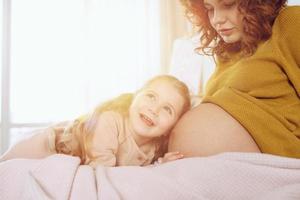 zwanger mam Toneelstukken met haar dochter. concept van familie, vreugde en zwangerschap foto