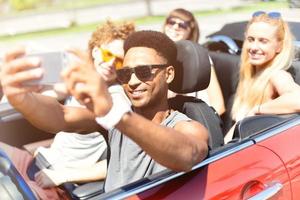 jong vrienden nemen een selfie in een cabriolet auto foto