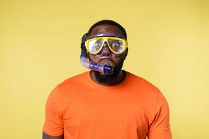 Mens met snorkelen masker is bang naar Gaan onderwater. geel achtergrond foto