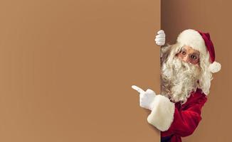 de kerstman claus geeft aan een blanco ruimte voor uw tekst foto