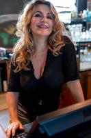 glimlachen blond aantrekkelijk volwassen vrouw werken met computer Aan de teller foto