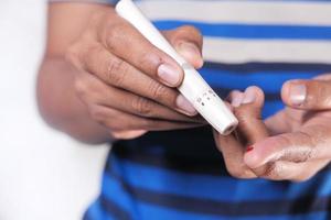 jonge man hand meten glucosespiegel geïsoleerd op een witte achtergrond foto