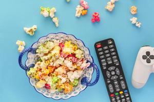 kleurrijke popcorn met afstandsbediening en controller op blauwe achtergrond foto