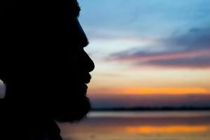 close-up silhouet van een man alleen op de bank voor de zee foto