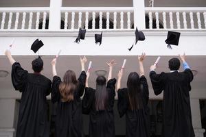 groep succesvolle studenten afstuderen hoeden in de lucht gooien en vieren foto