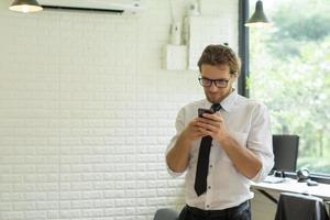 jonge zakenman met behulp van smartphone tijdens het werken op kantoor foto