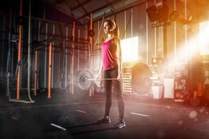 atletisch meisje werken uit Bij de Sportschool met een barbell foto