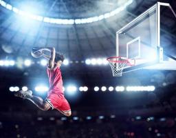 jumping speler gooit de bal in de mand in de stadion vol van toeschouwers foto