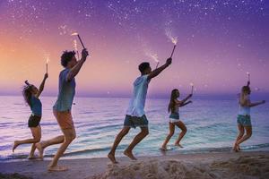 gelukkig glimlachen vrienden rennen Bij de strand met sprankelend kaarsen foto