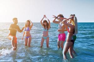 groep van vrienden hebben pret Aan de strand. concept van zomertijd foto