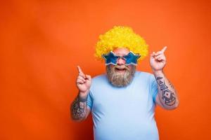 dik gelukkig Mens met baard, tatoeages en zonnebril dansen muziek- Aan een disco foto