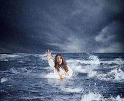 zakenvrouw in de oceaan met reddingsboei vraagt helpen gedurende een storm foto