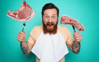 Mens met tatoeages is klaar naar eten vlees met bestek in hand. cyaan achtergrond foto