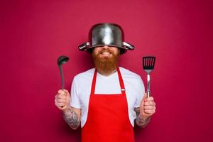 gelukkig chef met baard en rood schort is klaar naar koken foto