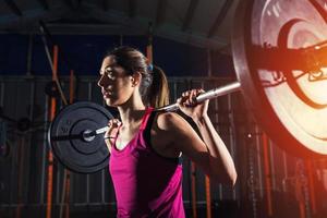 atletisch meisje werken uit Bij de Sportschool met een barbell foto