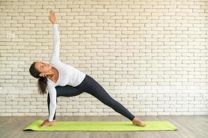 latijnse vrouw die yoga beoefent op mat foto