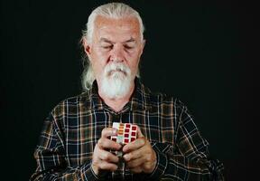 oud Mens is spelen met rubiks kubus spel foto