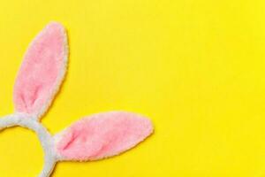 gelukkig Pasen concept. decoratief konijn oren harig kostuum speelgoed- geïsoleerd Aan modieus geel achtergrond foto