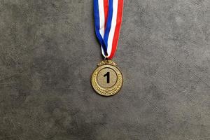 eenvoudig vlak leggen ontwerp winnaar of kampioen goud trofee medaille Aan beton steen grijs achtergrond. zege eerste plaats van wedstrijd. winnend of succes concept. top visie vlak leggen kopiëren ruimte. foto