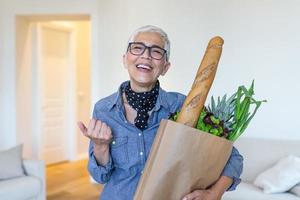 senior vrouw Holding papier zak vol van boodschappen schreeuwen trots en vieren zege en succes heel opgewonden, juichen emotie foto