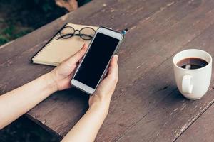 vrouw hand- Holding telefoon met blanco kopiëren ruimte scherm voor uw reclame. hand- vrouw gebruik makend van telefoon in koffie winkel. foto