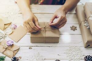 vrouw hand- maken mooi Kerstmis geschenk doos Bij tafel foto