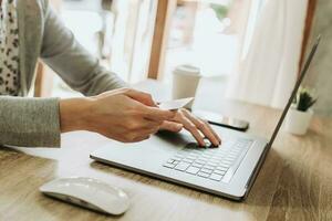 vrouw gebruik makend van credit kaart Aan laptop voor boodschappen doen online foto