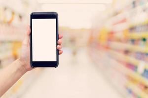 hand- vrouw Holding en tonen telefoon met wazig achtergrond in boodschappen doen winkelcentrum. foto