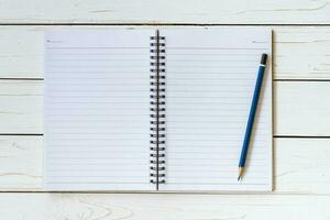 Open notitieboekje met blanco Pagina's en potlood Aan hout tafel foto