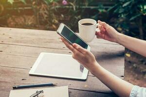 dichtbij omhoog van vrouw hand- Holding telefoon met blanco kopiëren ruimte scherm voor uw reclame. hand- vrouw gebruik makend van telefoon in koffie winkel. foto