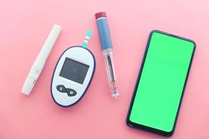 insuline en slimme telefoon op roze achtergrond foto