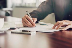 bedrijf Mens hand- schrijven Notitie papier Aan houten tafel foto