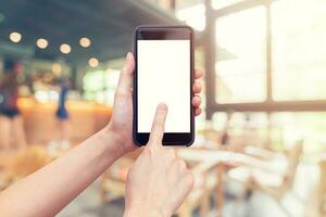 dichtbij omhoog hand- Holding telefoon blanco Scherm voor tekst en wazig koffie winkel achtergrond. foto