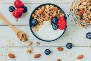 kom van muesli met yoghurt, vers bessen, bosbessen en noot Aan hout tafel. foto