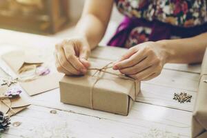 vrouw hand- maken mooi Kerstmis geschenk doos Bij tafel foto