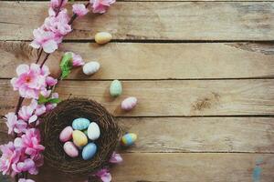 kers bloesem kunstmatig bloemen en Pasen ei in nest Aan wijnoogst houten achtergrond met kopiëren ruimte. foto