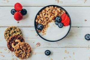 kom van muesli met yoghurt, vers bessen, aardbei Aan hout tafel. foto