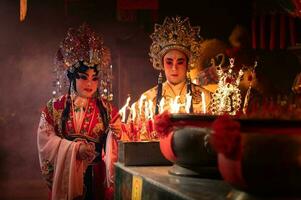 mannetje en vrouw Chinese opera acteurs licht een kaars naar bidden hulde naar de goden naar verbeteren de welvaart voor jezelf Aan de gelegenheid foto