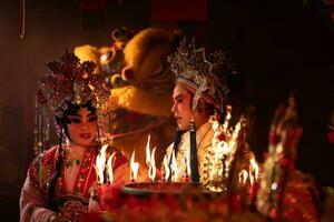 mannetje en vrouw Chinese opera acteurs licht een kaars naar bidden hulde naar de goden naar verbeteren de welvaart voor jezelf Aan de gelegenheid foto