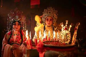 mannetje en vrouw Chinese opera acteurs licht een kaars naar bidden hulde naar de goden naar verbeteren de welvaart voor jezelf Aan de gelegenheid foto