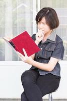 jong vrouw lezing boek zittend Aan stoel foto