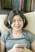 Aziatisch vrouw luisteren muziek- van mobiel telefoon foto