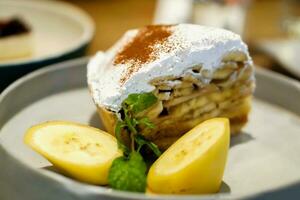 banaan banoffee taart met bananen plak en pepermunt bladeren Aan grijs keramisch bord en wazig achtergrond. foto