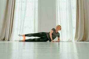 sportief vrouw doet opwarming oefening Bij huis met elastisch foto
