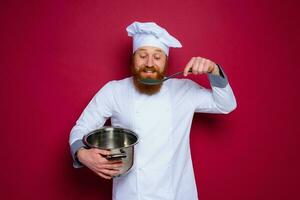 gelukkig chef met baard en rood schort is klaar naar koken foto