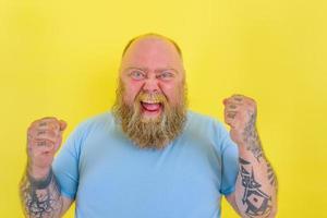 gelukkig Mens met baard en tatoeages doet een winnend gebaar met handen foto