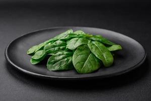 vers groen spinazie bladeren Aan een zwart keramisch bord foto