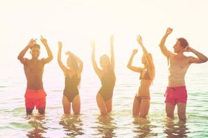 groep van vrienden dansen Aan de strand foto