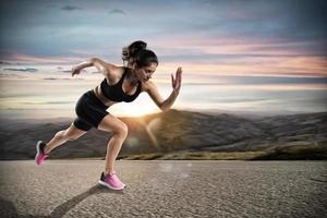 atletisch vrouw loopt Aan de straat gedurende zonsondergang foto